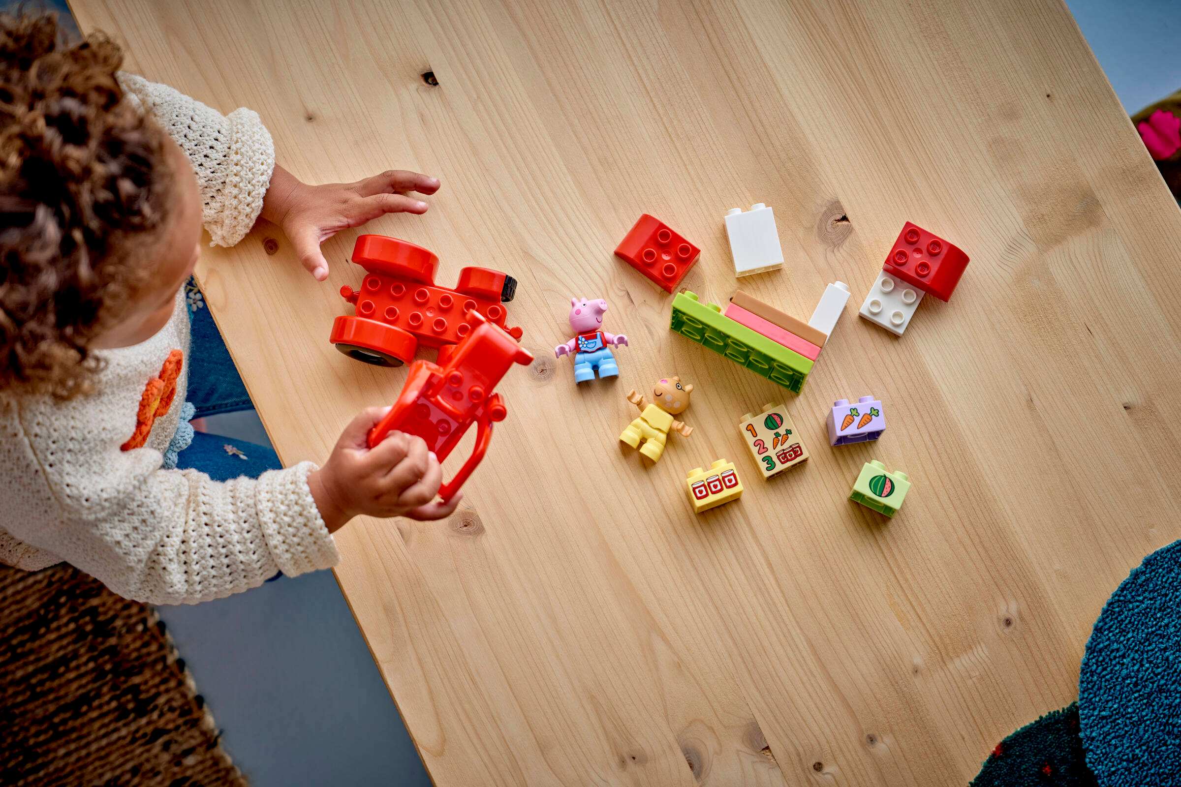 Дитина грається з конструктором LEGO DUPLO Свинка Пеппа Трактор і ринок 10468