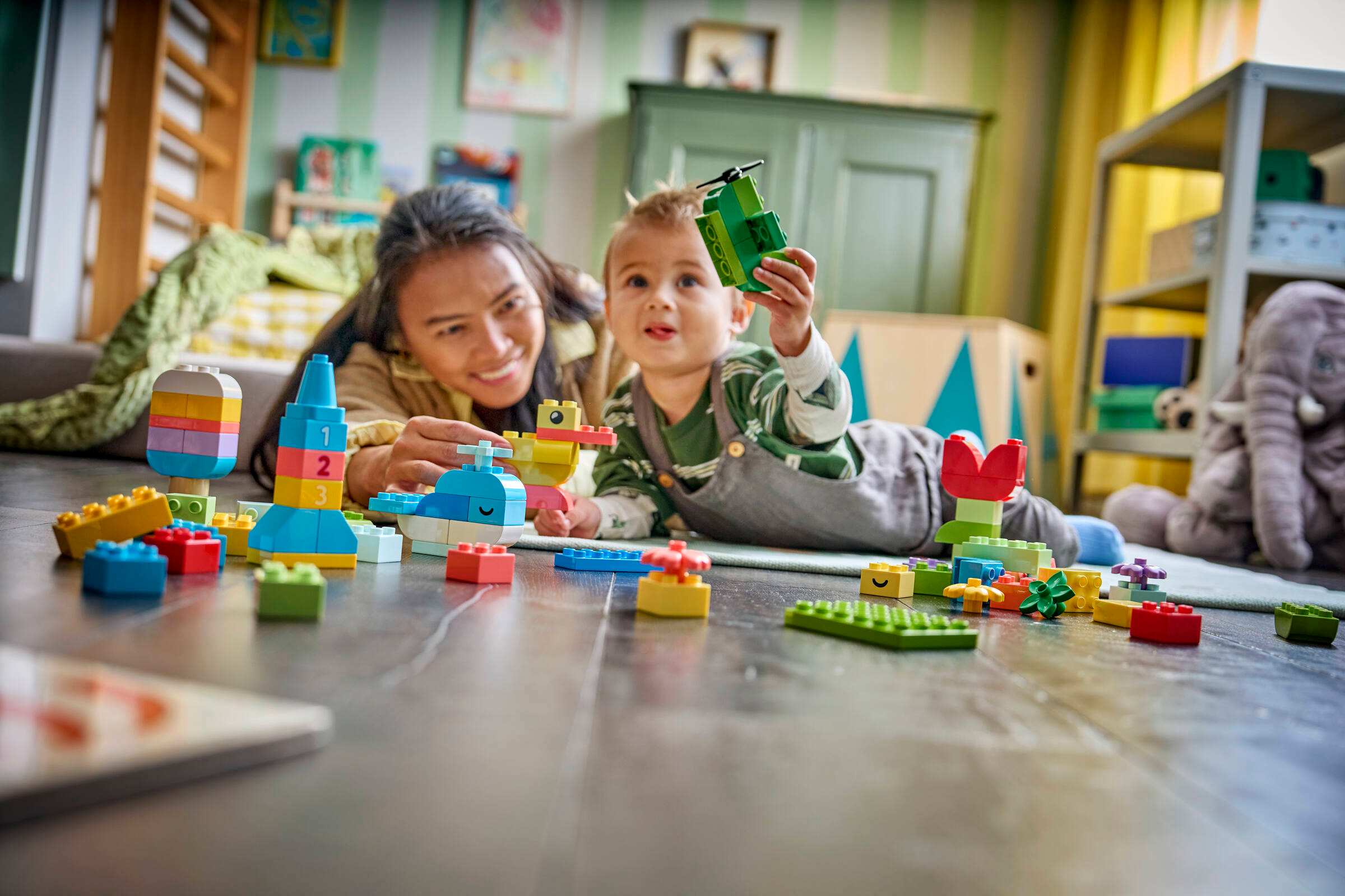 Ребенок играет со сборной уткой и ракетой из деталей LEGO 10479